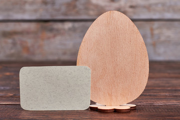 Plywood egg and blank card. Empty paper on wooden surface. Easter message ideas.