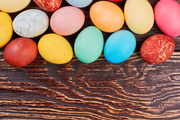 Brown wood background, Easter eggs. Colorful chicken eggs.