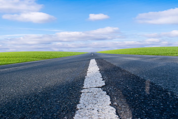 Asphalt road with green field and blue sky