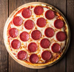 Italian Pepperoni pizza with salami on dark wooden background top view. Italian traditional food. Popular street food.
