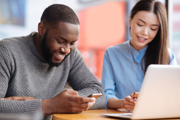 Young man and woman using smartphones at cafe