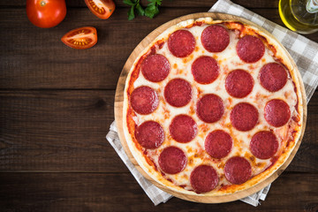 Italian Pepperoni pizza with salami on dark wooden background top view. Italian traditional food. Popular street food.