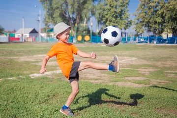 Foto op Plexiglas little boy in orange shirt playing soccer, kicking the ball © vitec40