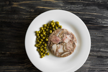 Headcheese with peas on a wooden table. Tasty and nutritious dish.