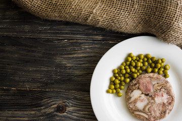 Headcheese with peas on a wooden table. Tasty and nutritious dish.