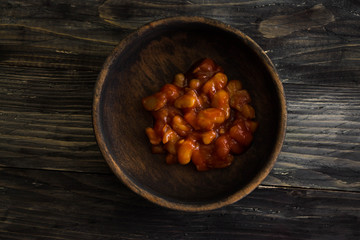 Beans in tomato in a wooden bowl. A delicious dish.
