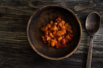 Beans in tomato in a wooden bowl. A delicious dish.