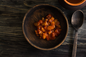 Beans in tomato in a wooden bowl. A delicious dish.