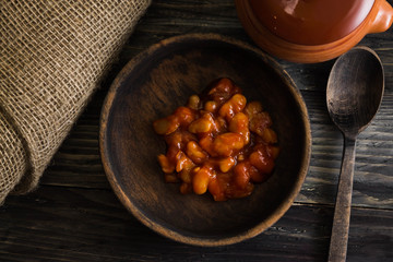 Beans in tomato in a wooden bowl. A delicious dish.