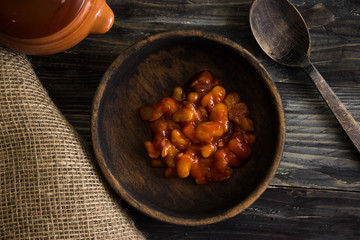 Beans in tomato in a wooden bowl. A delicious dish.