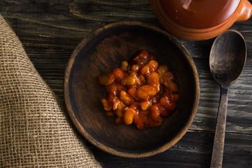 Beans in tomato in a wooden bowl. A delicious dish.