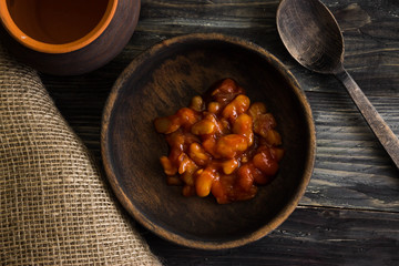 Beans in tomato in a wooden bowl. A delicious dish.