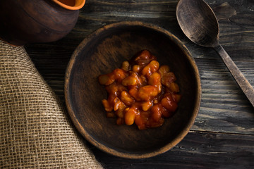 Beans in tomato in a wooden bowl. A delicious dish.