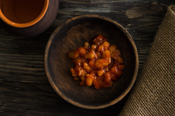 Beans in tomato in a wooden bowl. A delicious dish.