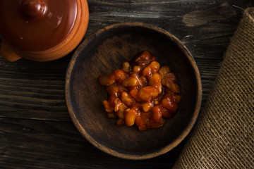 Beans in tomato in a wooden bowl. A delicious dish.