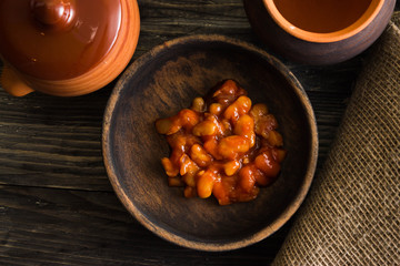Beans in tomato in a wooden bowl. A delicious dish.