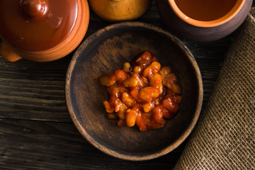 Beans in tomato in a wooden bowl. A delicious dish.
