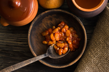 Beans in tomato in a wooden bowl. A delicious dish.