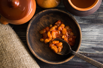 Beans in tomato in a wooden bowl. A delicious dish.