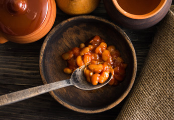 Beans in tomato in a wooden bowl. A delicious dish.