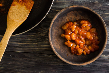 Beans in tomato in a wooden bowl. A delicious dish.