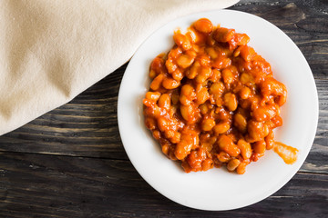 Beans in tomato in a white plate. A delicious dish.