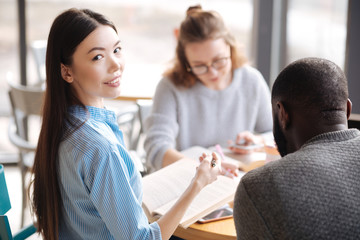 Happy female student studying with her fellows