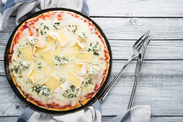 Italian pizza with different sorts of cheese on old wooden background top view. Italian traditional food. Popular street food.