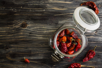 Dried chili pepper in a glass jar on a wooden table