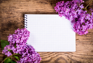Bunches of lilac on old table with blank notebook