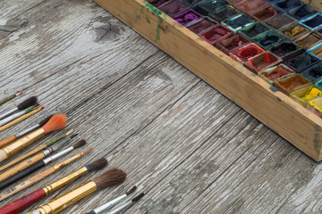 Obraz premium Box with watercolors and brushes on a wooden surface