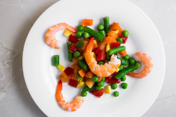 Shrimps with vegetables on a wooden table in rustic style