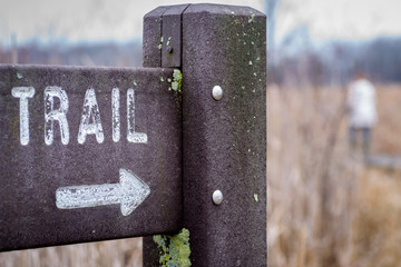 trailhead sign with arrow on a path in the woods