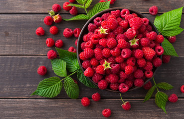 Red fresh raspberries on brown rustic wood background