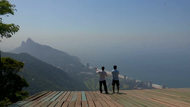 Two people observing beautiful scenery from the top of a mountain view