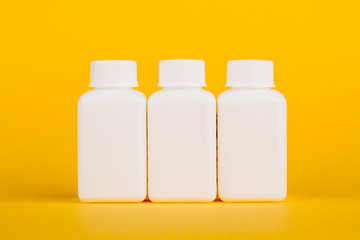 White medical bottles, on yellow background