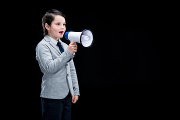 Adorable boy standing with megaphone and yelling on black