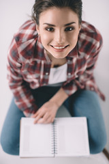 elevated view of smiling woman student with notebook in hands