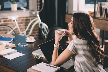 attractive woman with laptop drinking coffee
