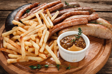 Delicious grilled sausages and french fries served with delicious sauce, close up view. German food, restaurant menu photo.