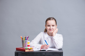 A schoolgirl sits at her desk and does homework