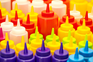 Background of multi-colored plastic bottles for sauce