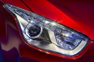 Car headlight with led and xenon lamps of modern sport car with red bodywork 