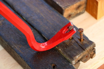 Red crowbar pulling a rusty nail to demonstrate the concept of leverage
