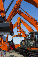 Bulldozer, excavator, tractor, front end loader and other orange construction machines with scoop, shovel, jackhammer and another equipment in row, heavy industry, blue on background