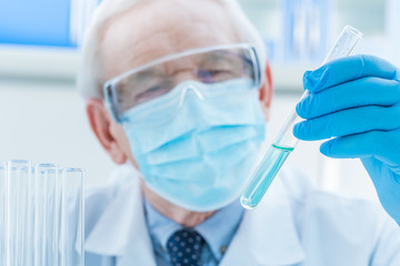 senior chemist looking at test tube in laboratory