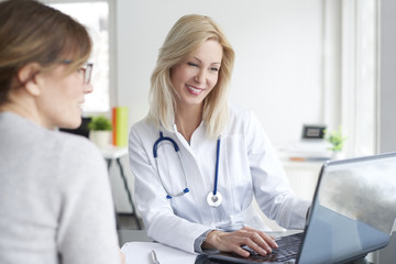 Doctor and her patient. Shot of a middle aged female doctor sitting in front of laptop and...