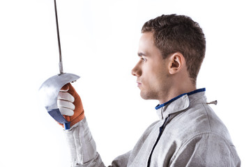 Side view of young man professional fencer holding rapier on white