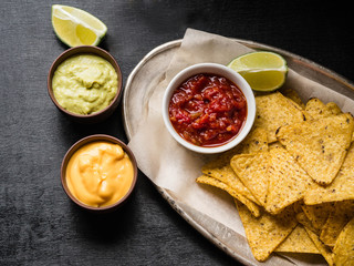 Mexican nachos chips  with salsa sauce in metal plate on dark background
