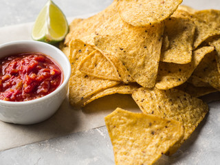Mexican nachos chips  with salsa sauce and lime slice

